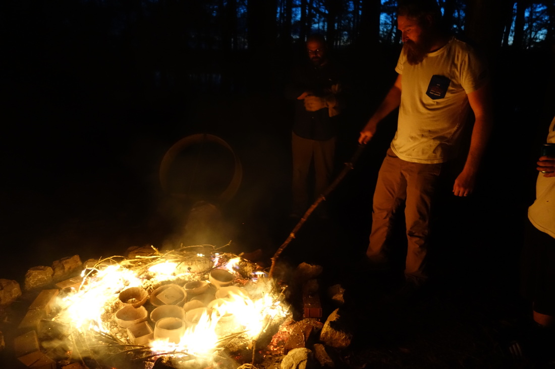 New College student Andrew Seymour tending the fire during an outdoor pottery firing at Moundville State Park