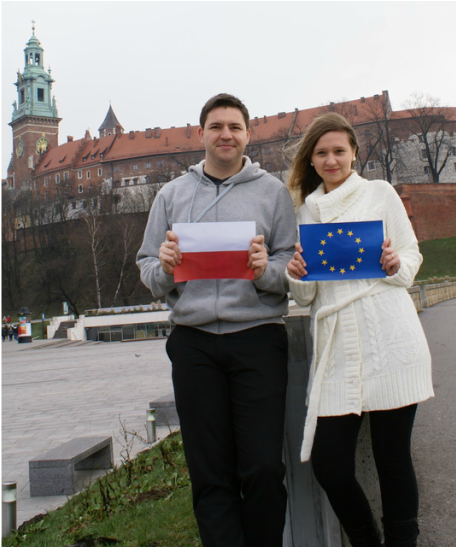 A young Polish couple in front of Wawel Castle, Krakow holding up the Polish and European Union Flags